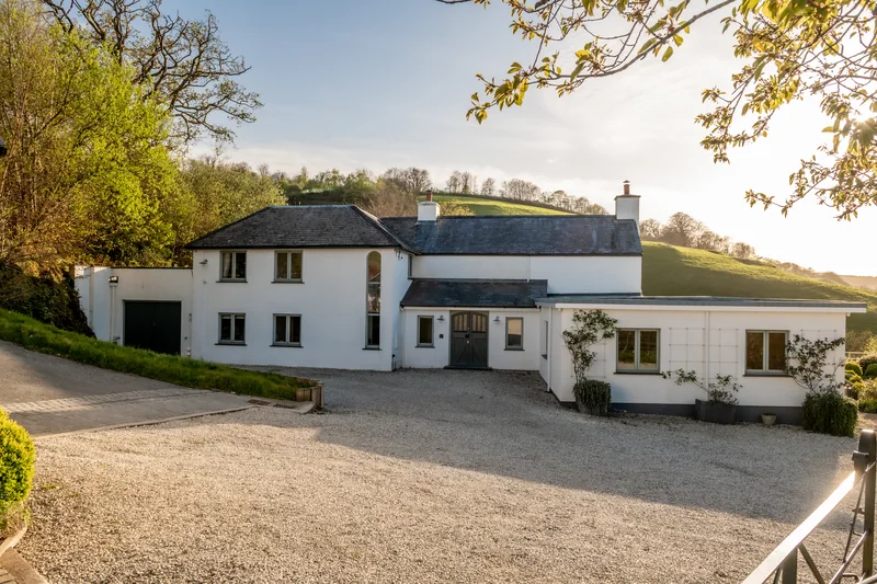 The white exterior of Lakeview Farmhouse beneath a leafy tree