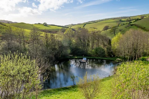 The Longlands lake surrounded by woodland and rolling green hills