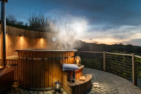 Steam rising from a wooden hot tub on its deck above the valley
