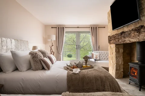 Farmhouse bedroom with a stone fireplace and doors opening to the garden