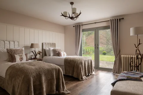 A spacious Farmhouse bedroom with a stone fireplace and garden doors