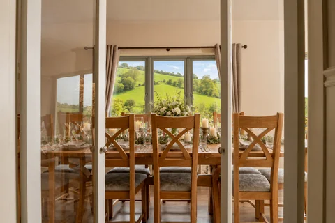 The Farmhouse sun room and dining table seen through an open doorway
