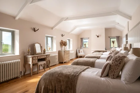A spacious bedroom with neutral bedding and several windows
