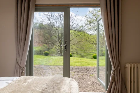 Garden views through French doors beside a Farmhouse bed