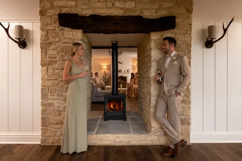 A groom standing beside the Farmhouse stone fireplace