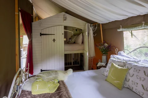 A Safari Lodge bedroom with soft bedding beneath the canvas walls