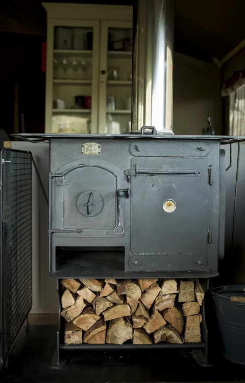 A wood-burning stove and stacked logs inside a Safari Lodge