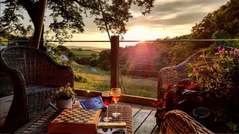 A glass and lantern on a lodge deck at sunset