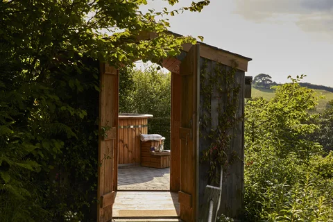 The wooden sauna with a glazed door beside the countryside deck
