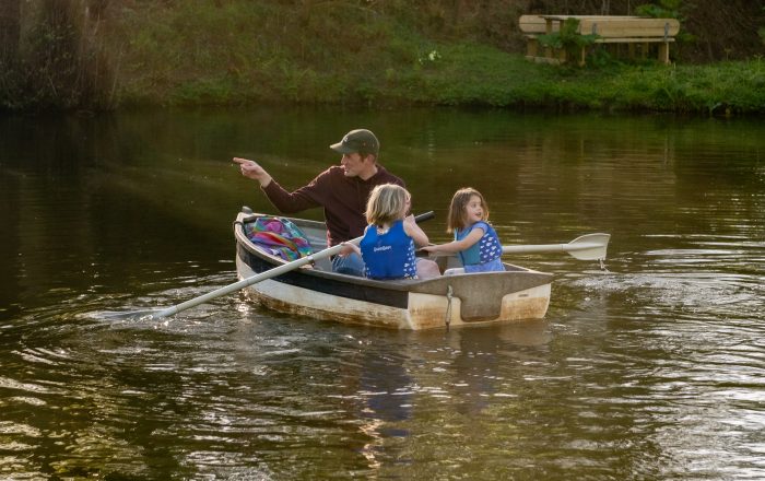 Children rowing boat on private lake at Longlands Devon with jetty and swimming area