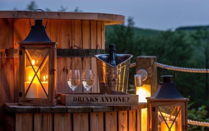 Private hot tub deck at Longlands Devon with lantern light and drinks at dusk
